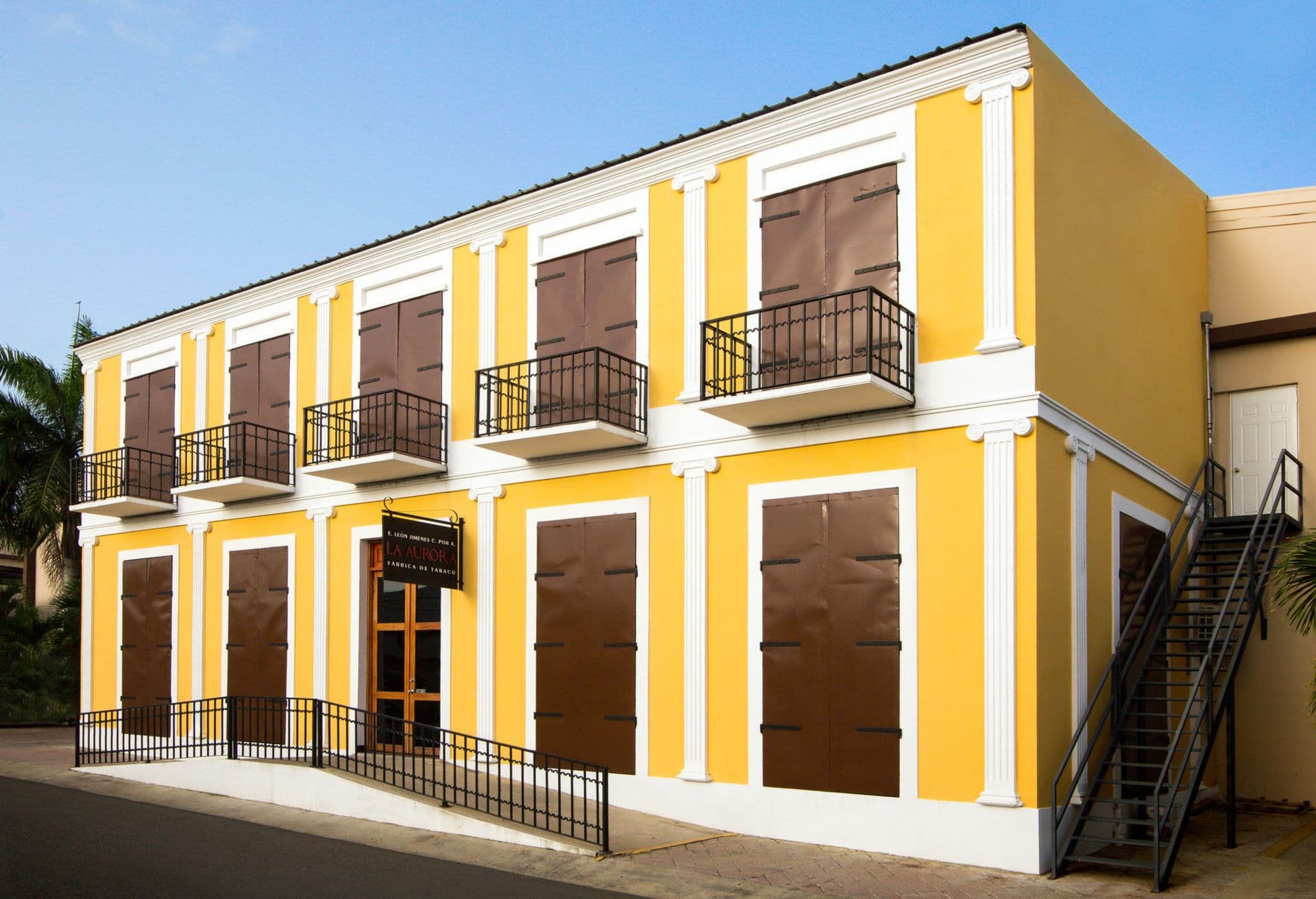 Grupo de turistas observando a un experto torcedor de puros trabajar en la centenaria fábrica de tabaco La Aurora en Santiago de los Caballeros, República Dominicana.